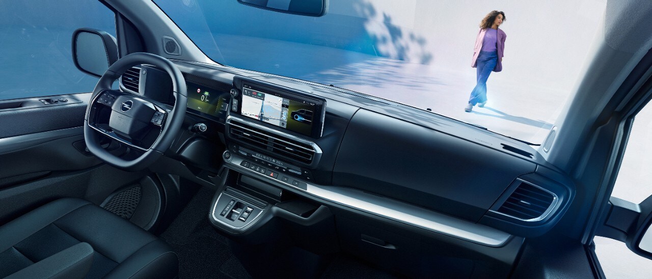 Поглед во внатрешноста на бела Opel Zafira Electric од севозачко седиште со жена која стои надвор