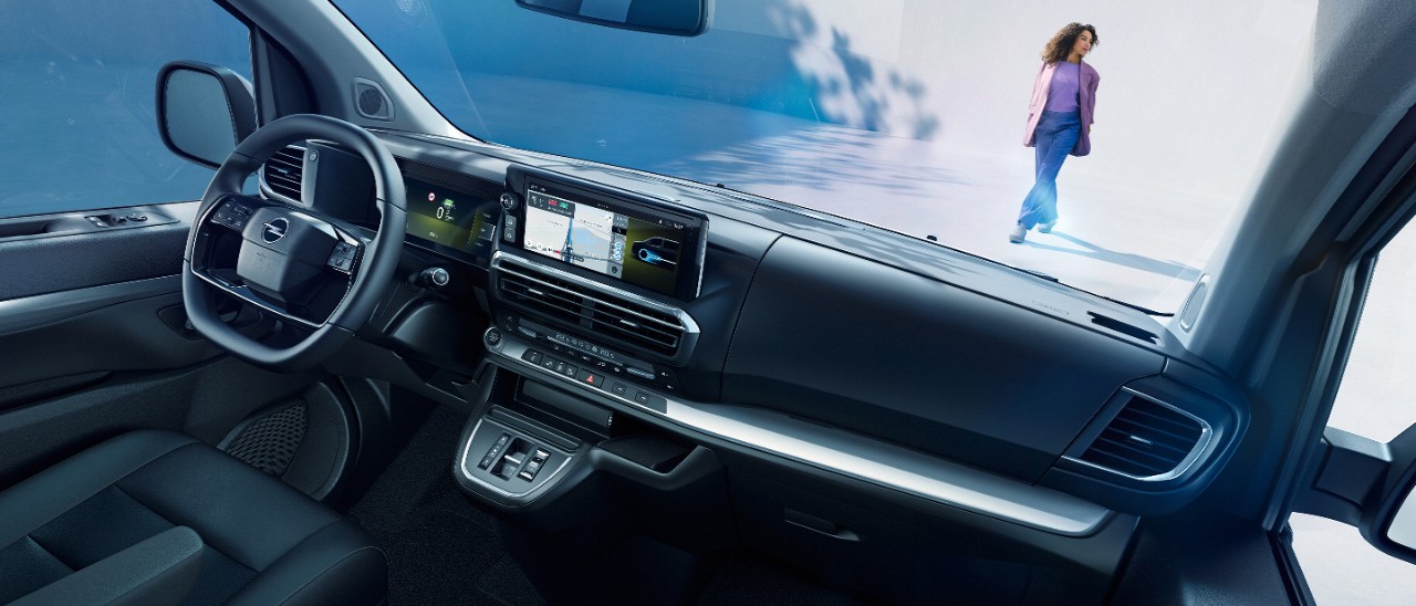 Поглед во внатрешноста на бела Opel Zafira Electric од севозачко седиште со жена која стои надвор